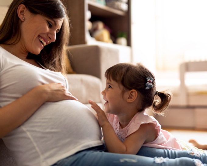 Pregnant Mother Laughing with Young Daughter Pregnant Mother Laughing with Young Daughter